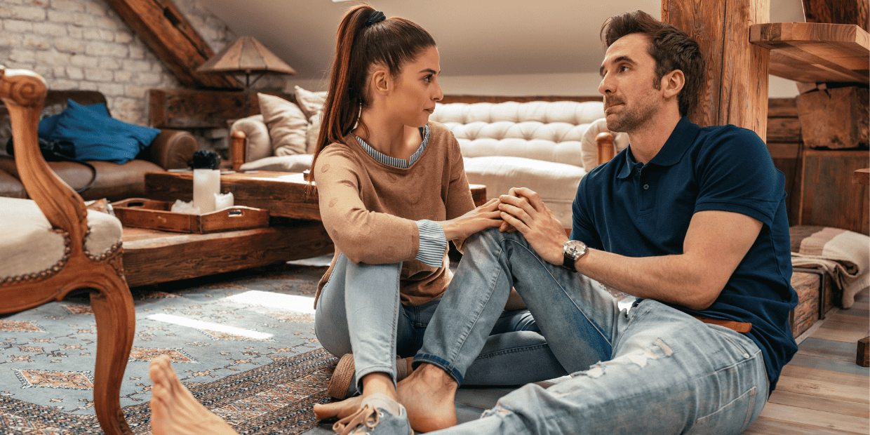 Woman and man sitting on floor having a serious conversation.
