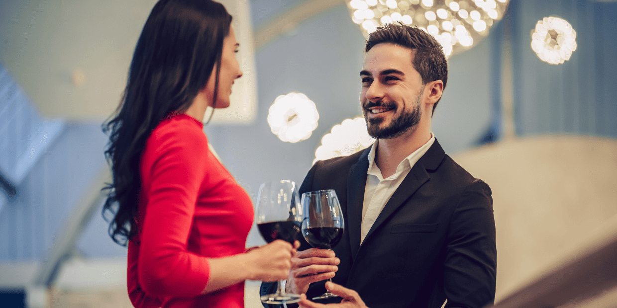 Photo of a man and woman holding wine glasses and talking.