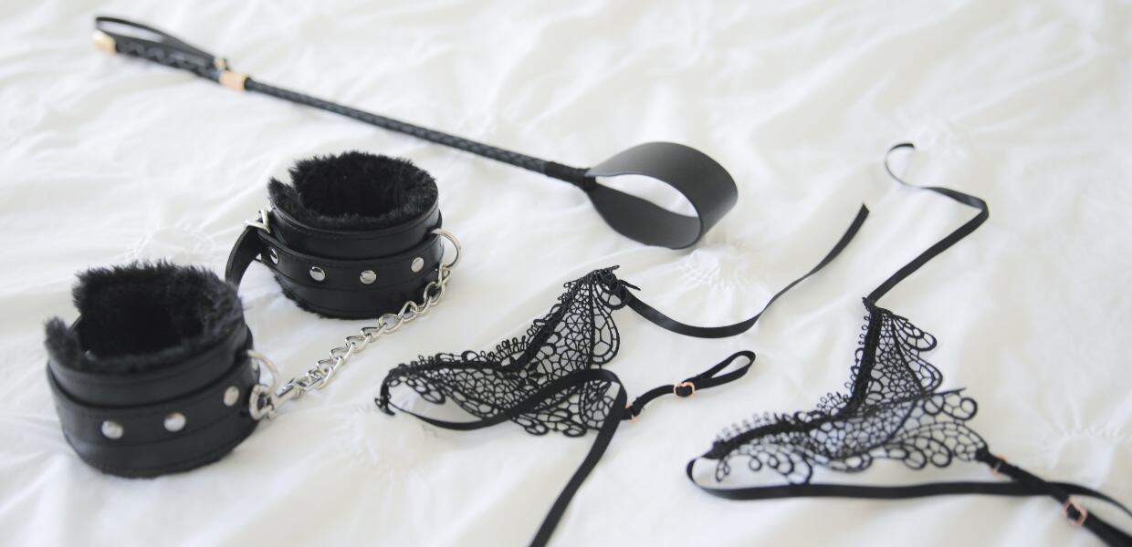 Photo of lingerie, handcuffs, and a whip.