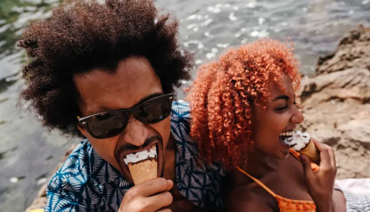 Photo of Black couple eating ice cream together and laughing