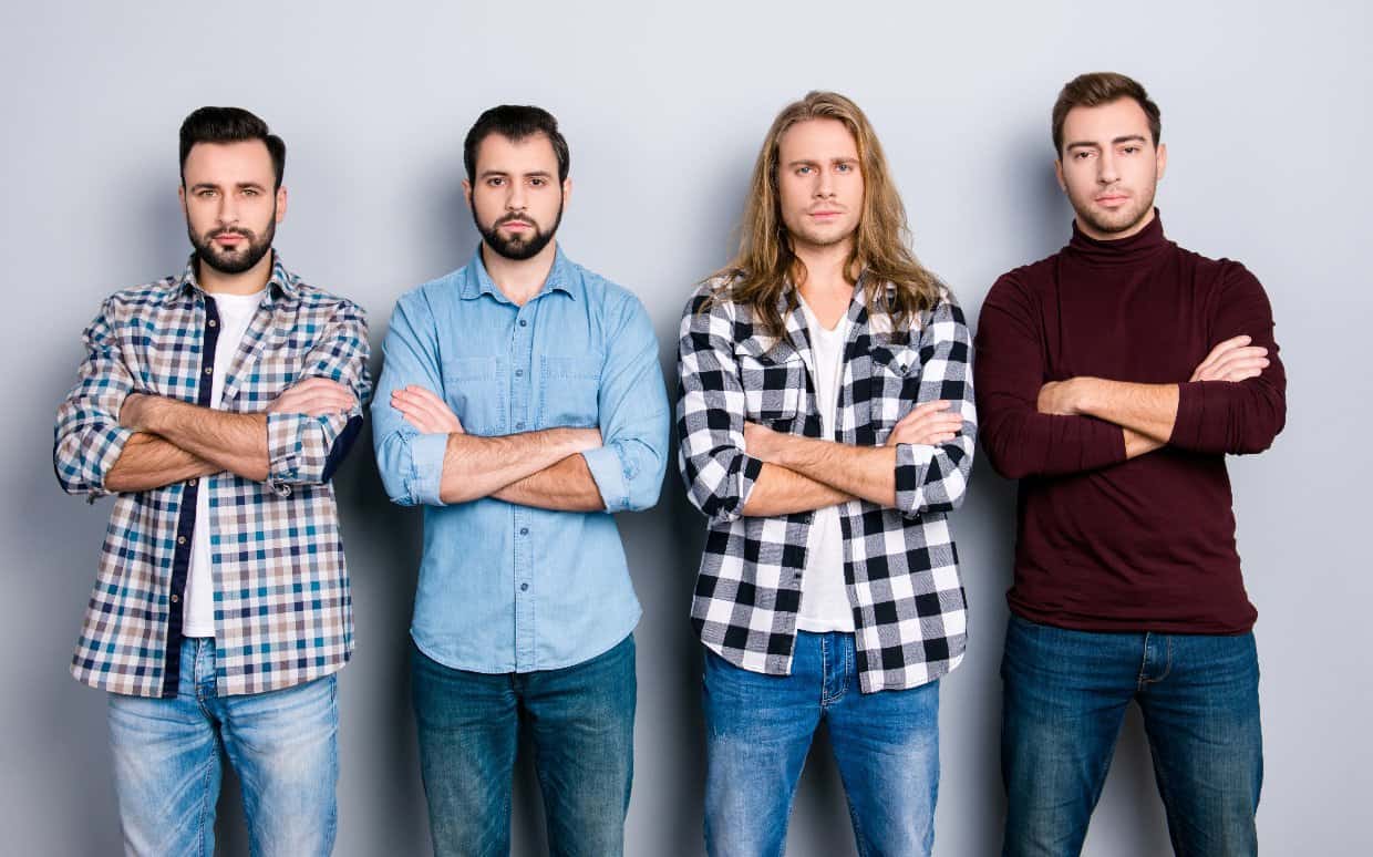 Stock photo of four men with serious expressions standing in a row and crossing their arms