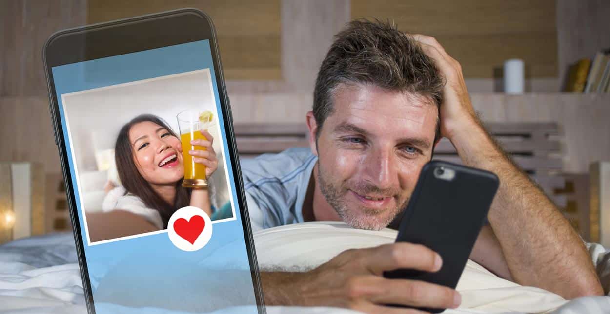 Man looking at a photo of a woman on his phone and smiling
