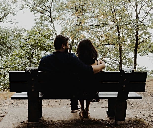 Photo of a man with his arm around a woman on a park bench
