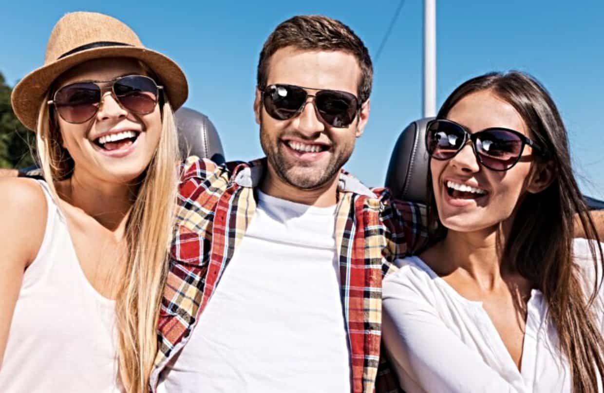 Man laughing with two women wearing sunglasses