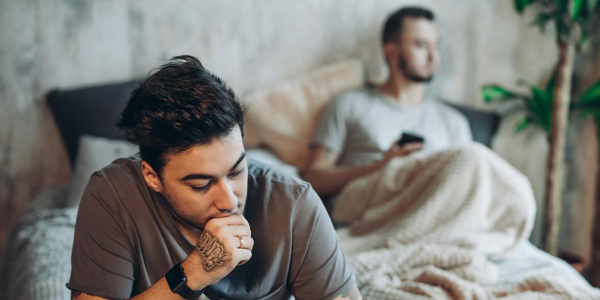 Photo of sad gay couple on a bed
